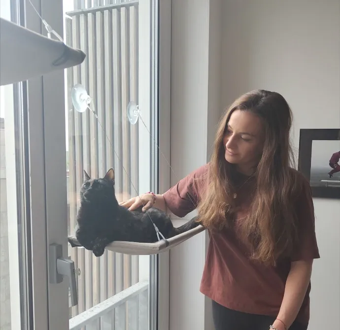 Fanny caresse Maya, installée dans un hamac accroché à la fenêtre.